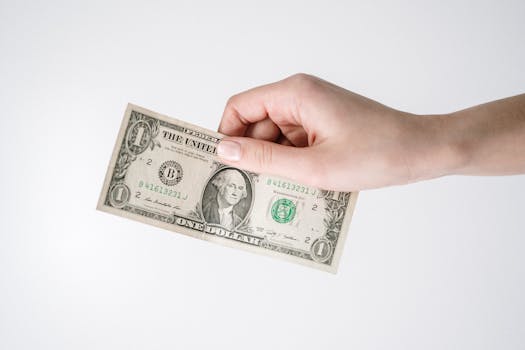 Close-up of a hand holding a one US dollar bill against a white background. Ideal for finance-related themes.