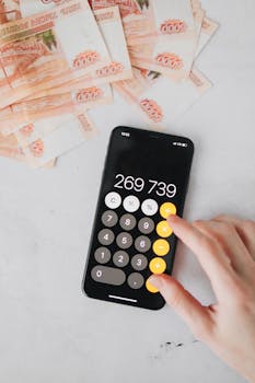 Close-up of smartphone calculator and ruble banknotes, illustrating financial calculations.